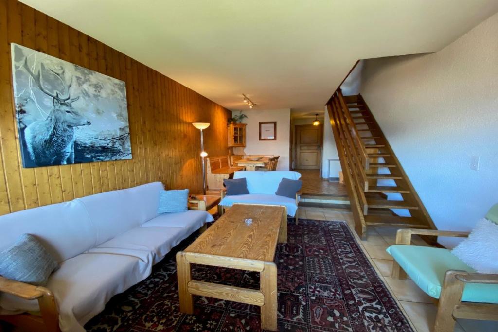 a living room with white couches and a wooden wall at Tourtereaux 223 in Verbier