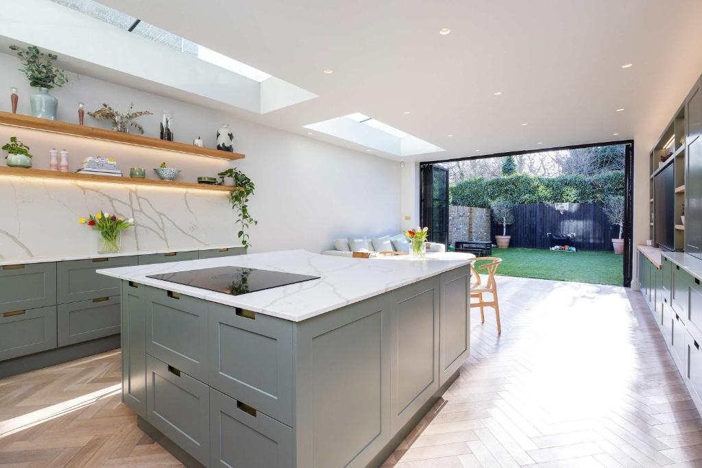 a kitchen with a large island in the middle at Veeve - A Symphony in Green in London