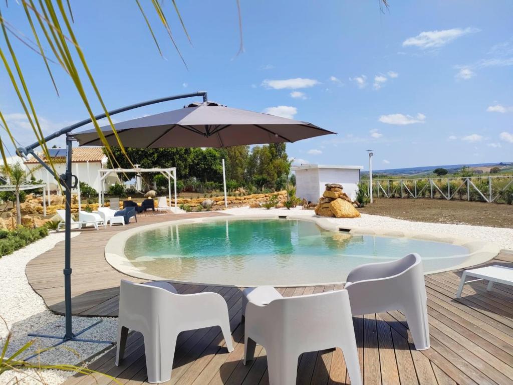 uma piscina com uma mesa e cadeiras e um guarda-sol em Il giardino di Afrodite em Marinella di Selinunte