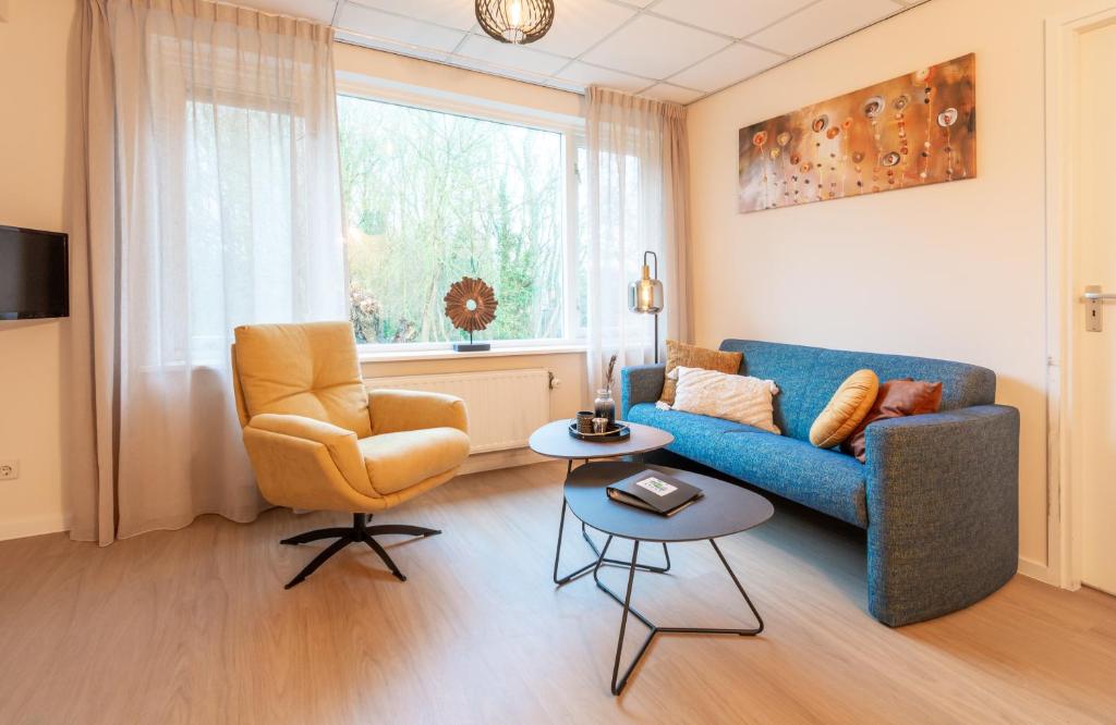 - un salon avec un canapé bleu et une chaise dans l'établissement Appartementen Zuiderstrand Zoutelande, à Zoutelande