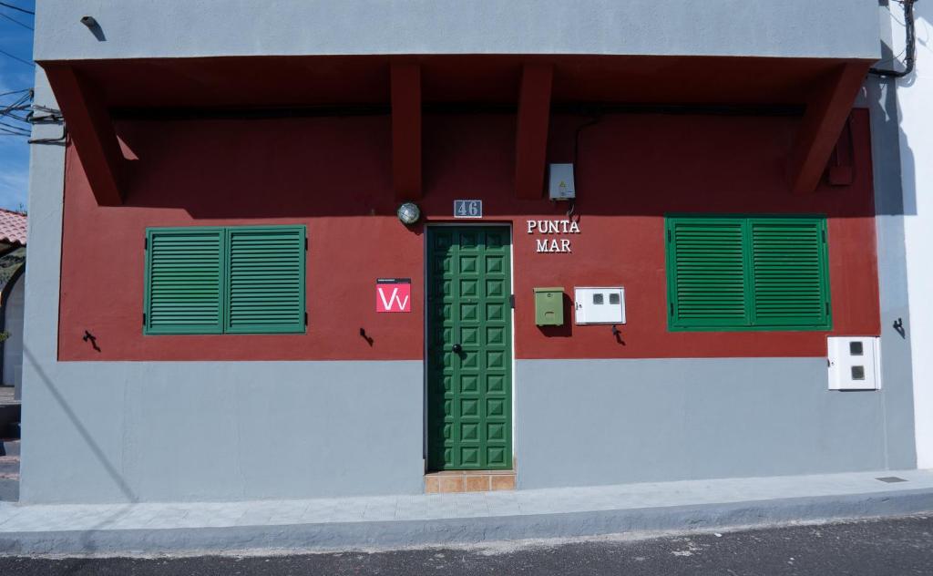 a red and white building with a green door and windows at Punta Mar in Güimar