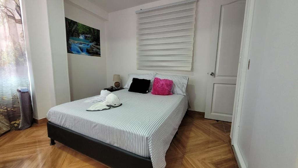 Schlafzimmer mit einem Bett mit rosa und schwarzen Kissen in der Unterkunft apartamento banderas 2 in Pereira