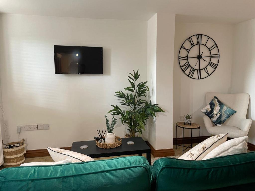sala de estar con 2 sofás verdes y reloj en The Old Bakery en South Cerney