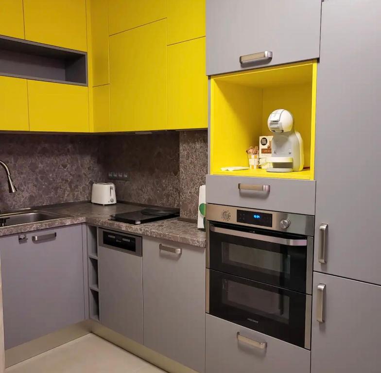 Una cocina con gabinetes amarillos y grises y una estufa. en Fully Furnished Apartment-B7, en Varna