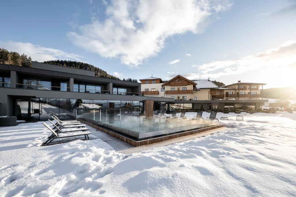a building with a pool in the snow at Hotel Viertler in Avelengo