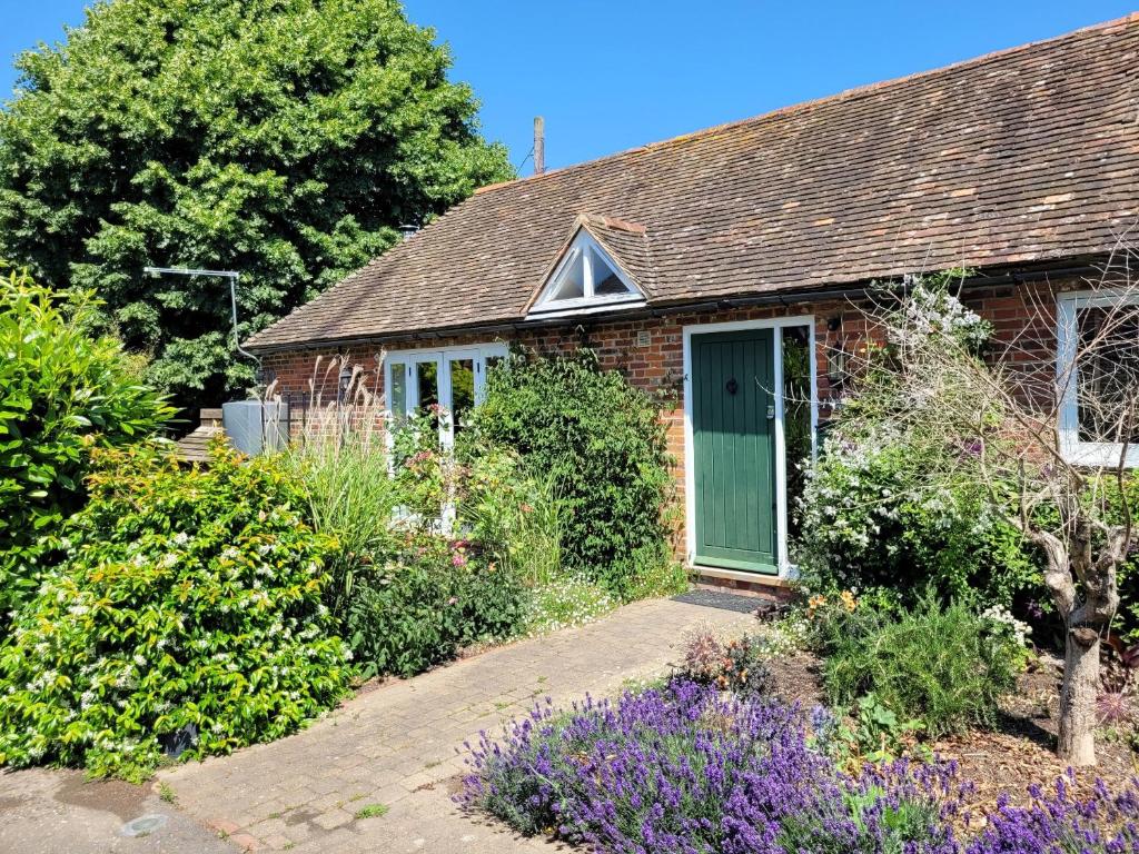 ein Backsteinhaus mit grüner Tür in einem Garten in der Unterkunft Little Ripple Cottage by Bloom Stays in Canterbury