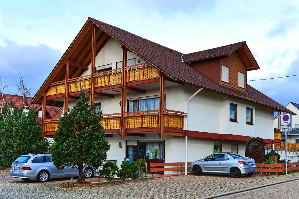 uma casa com dois carros estacionados em frente em Hotel Garni Sebastian em Kirrweiler