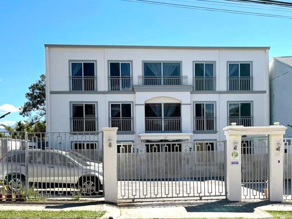 een wit huis met een hek en een auto voor de deur bij LOP Inn San Jose Aeropuerto - Costa Rica in Ciudad Cariari