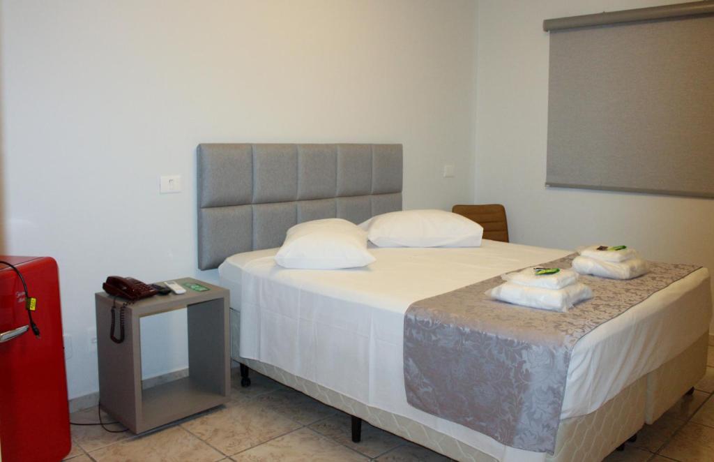 a bedroom with a bed with two pillows on it at Optimum Plaza Hotel in Monte Alto