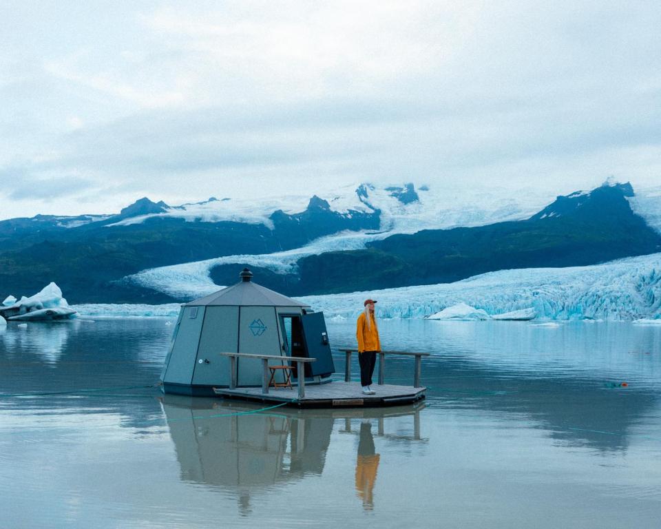 a man standing on a small boat in the water at Fjallsarlon - Overnight adventure in Hnappavellir
