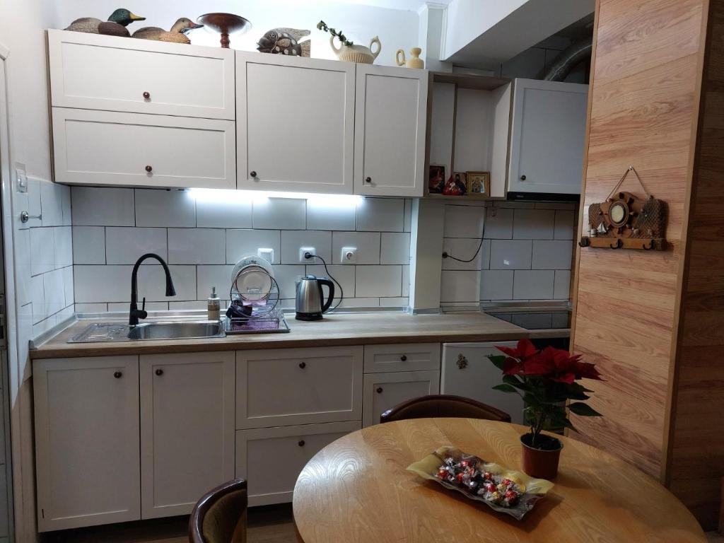 a kitchen with white cabinets and a wooden table at Студио Тони in Burgas