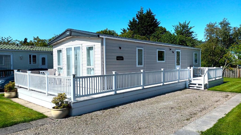 a mobile home with a white fence at Binka - Luxury 40 x 14ft Lodge in Tain