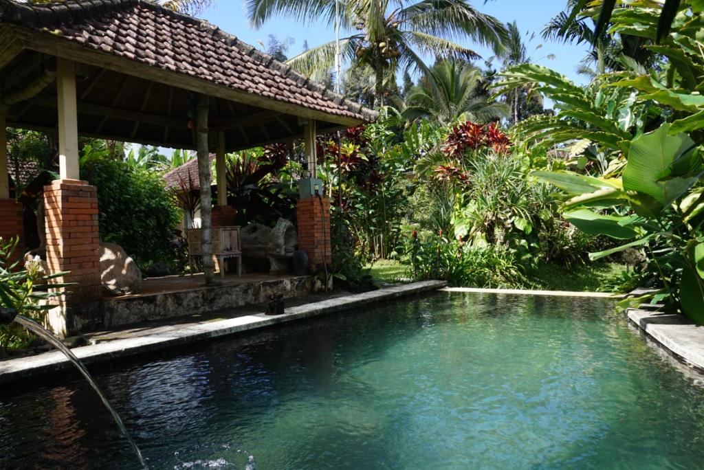 a swimming pool in a garden with a gazebo at Dewa Jati House in Penginyahan