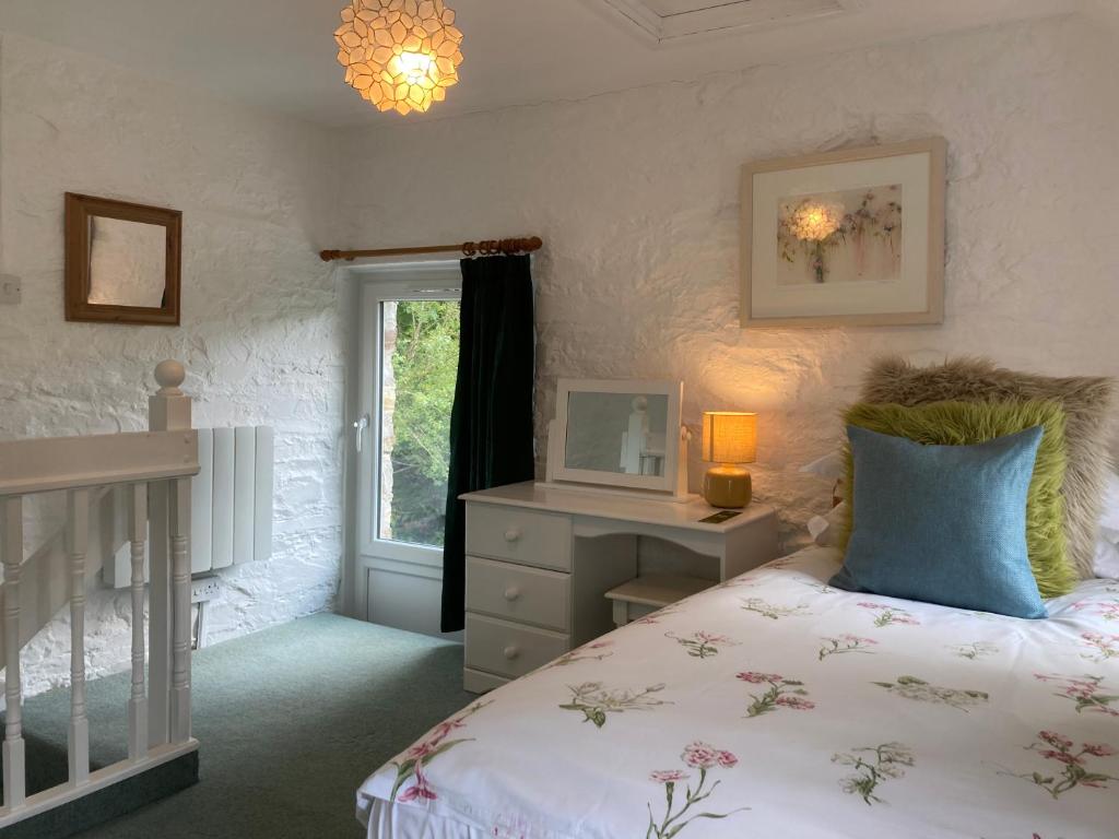 a bedroom with a bed and a desk and a window at The Old Farmhouse in Liskeard