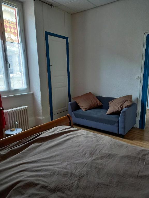 Cette chambre comprend un lit et un canapé bleu. dans l'établissement F1 Rez De Chausée, à Néris-les-Bains