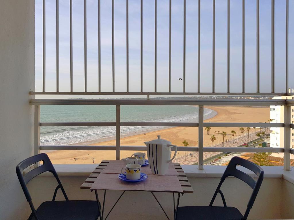 uma mesa e cadeiras com vista para a praia em Valdelagrana Mar Ha Apartment em El Puerto de Santa María