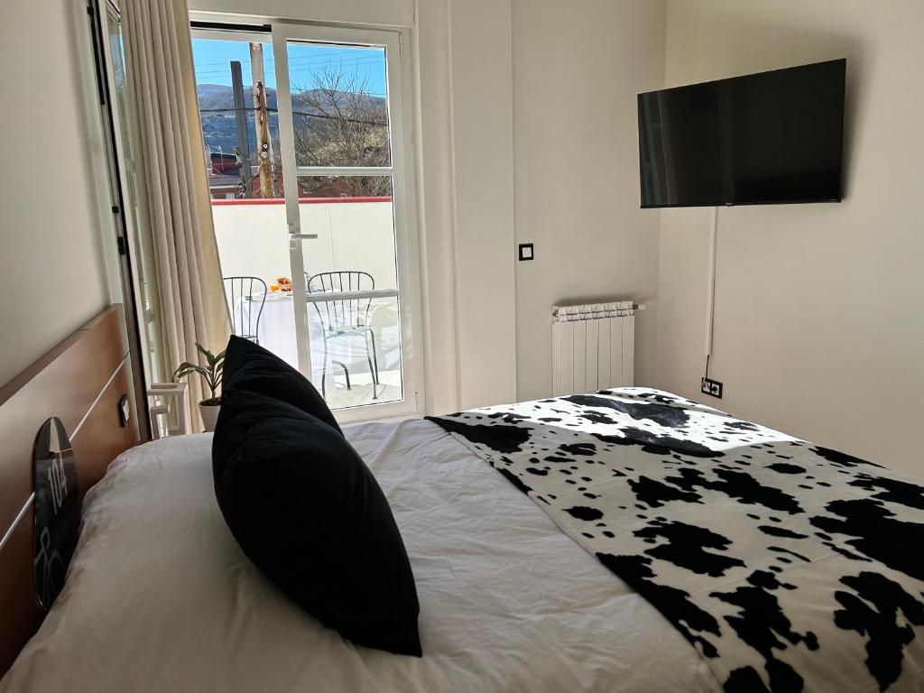 a bedroom with a black and white bed with a television at Bicis & Vacas in La Pola de Gordón