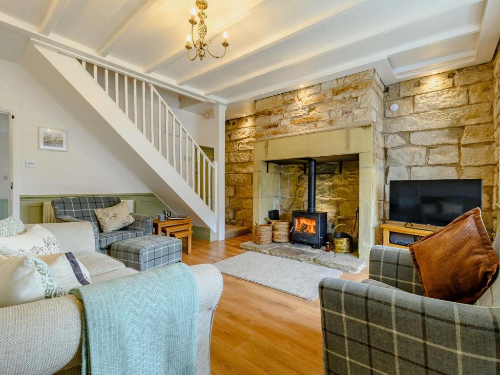 una sala de estar con 2 sofás y una chimenea de piedra. en 2 bed property in Rothbury Northumberland 89502 en Thropton