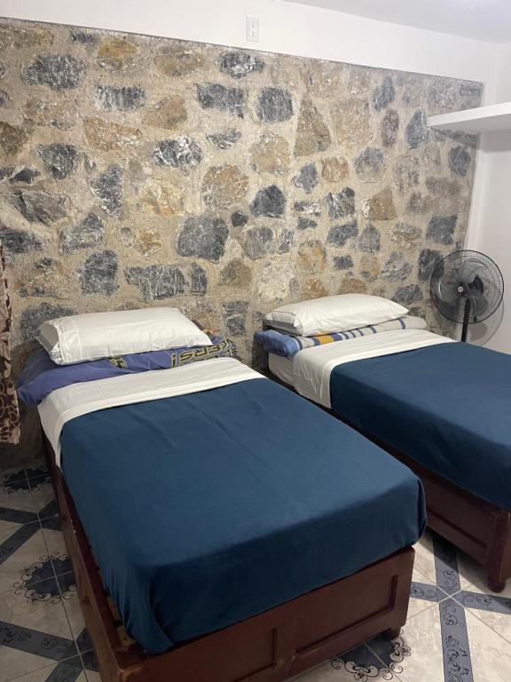 duas camas num quarto com uma parede de pedra em Departamentos huerta em Taxco de Alarcón
