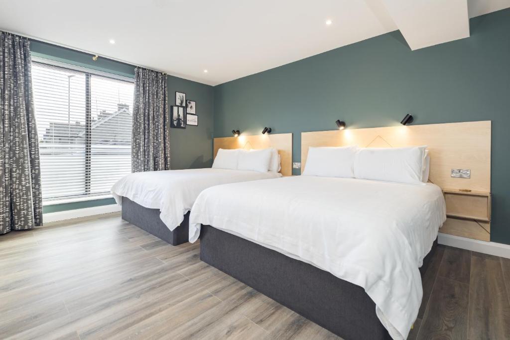 2 camas en un dormitorio con paredes azules en Port 56, en Portstewart