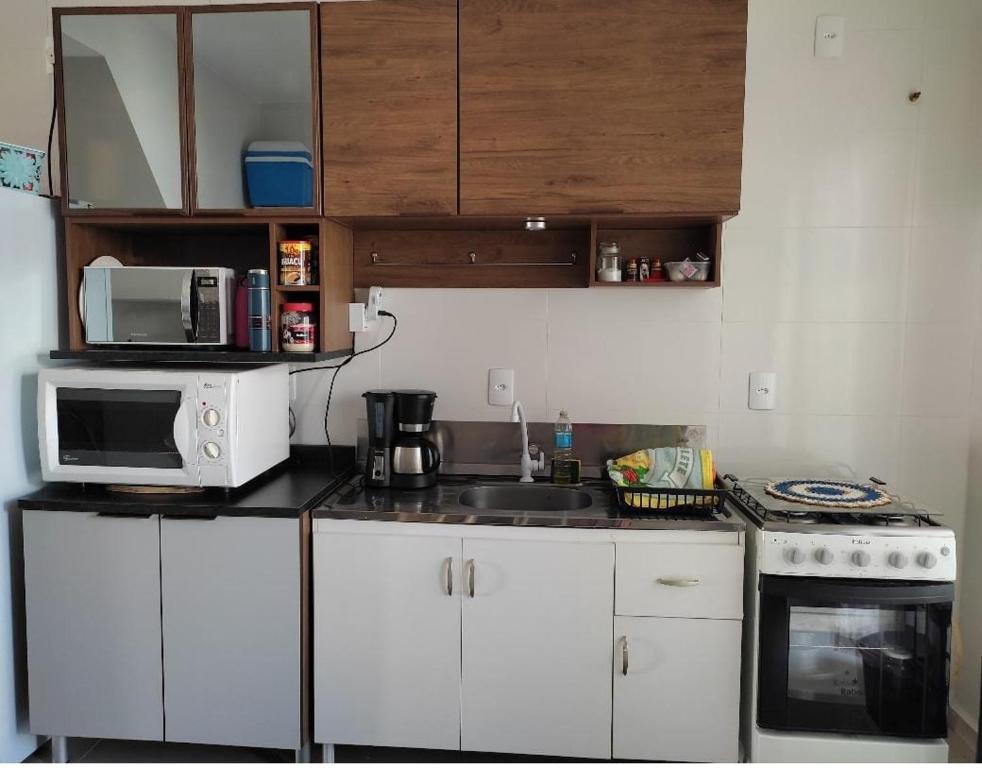 a small kitchen with a sink and a microwave at Geminado Ibicaré com quarto privativo em casa compartilhada in Joinville