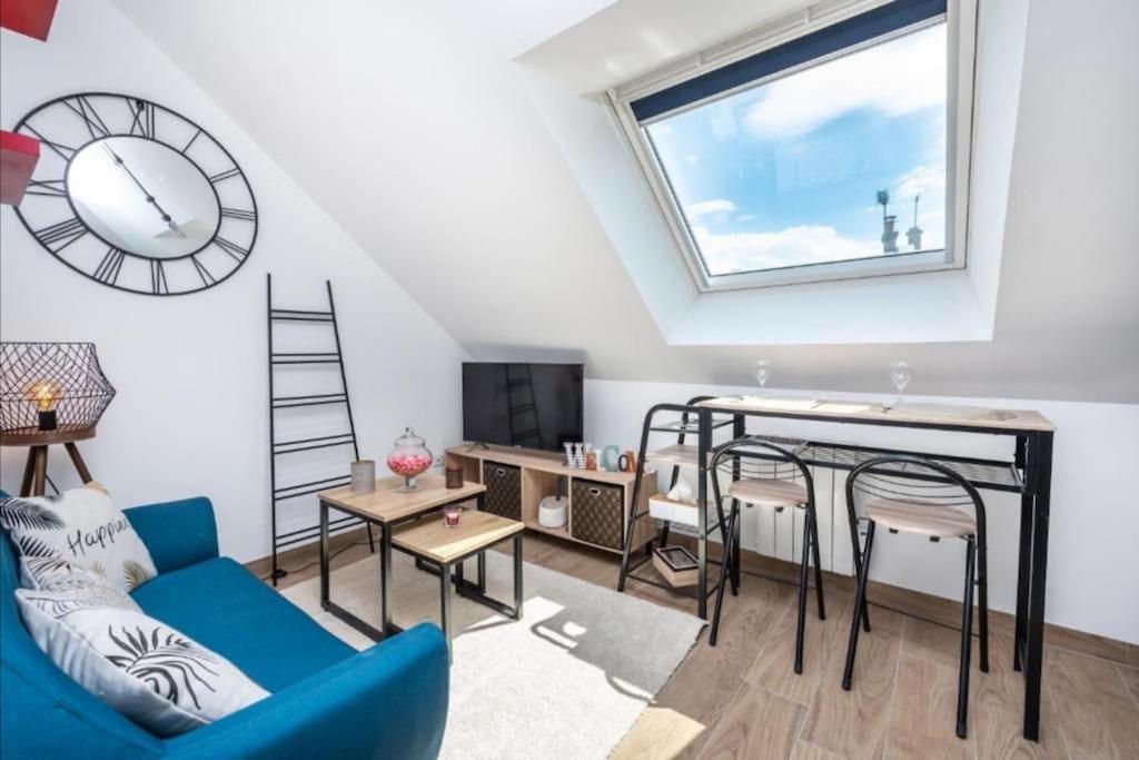a living room with a blue couch and a clock at Appartement Cosy Amiens in Amiens