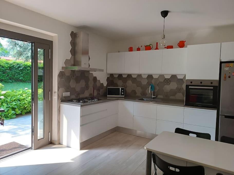 uma cozinha com armários brancos, uma mesa e uma janela em appartamento immerso nel verde tra laghi e colline em Anzano del Parco