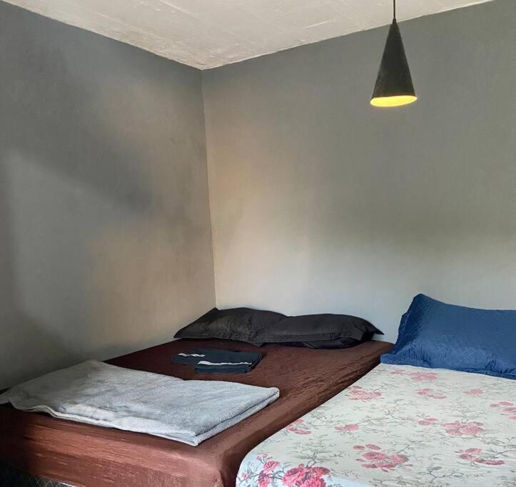 niewielka sypialnia z 2 łóżkami i lampką w obiekcie Quarto/sala Região central w mieście Macaé