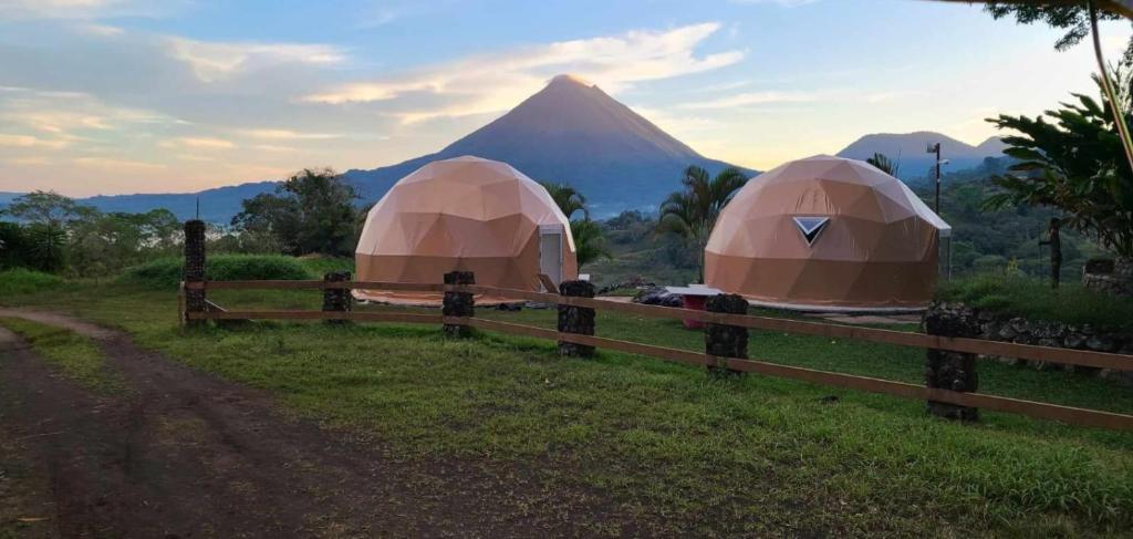 twee tenten in een veld met een berg op de achtergrond bij Pura Vista Glamping in El Castillo de La Fortuna