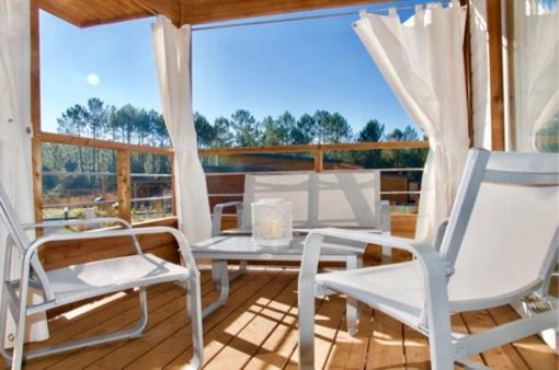 un patio avec deux chaises et une table sur une terrasse dans l'établissement Chalet 2 chambres en Bois dans les landes n34, à Tosse