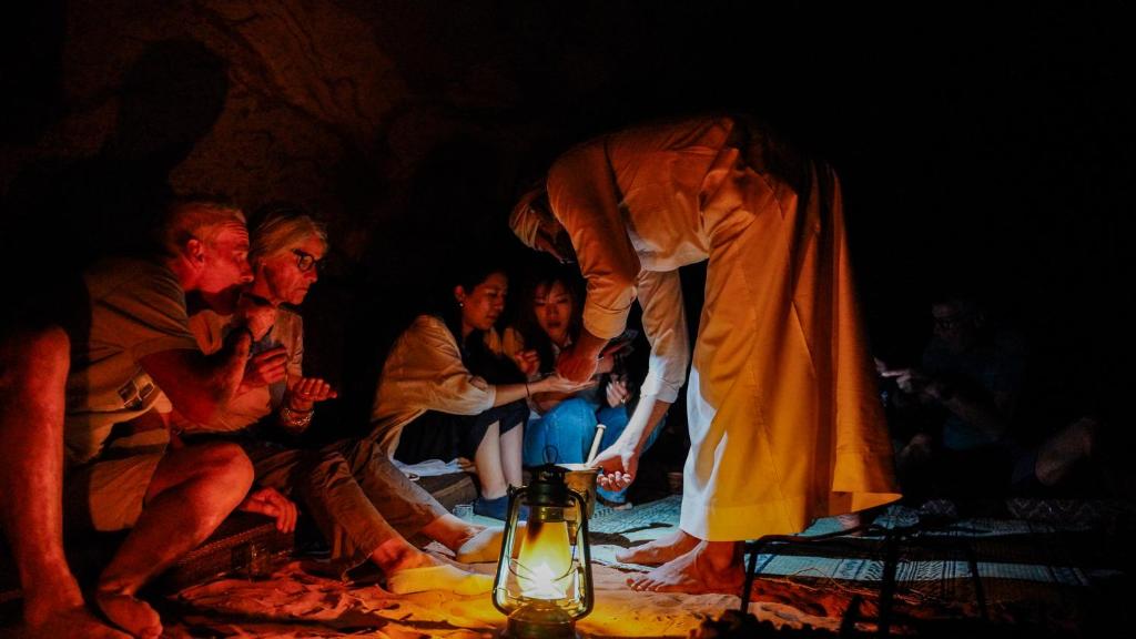 a man is lighting a lantern in front of a group of people at Wadi Rum Trail in Wadi Rum