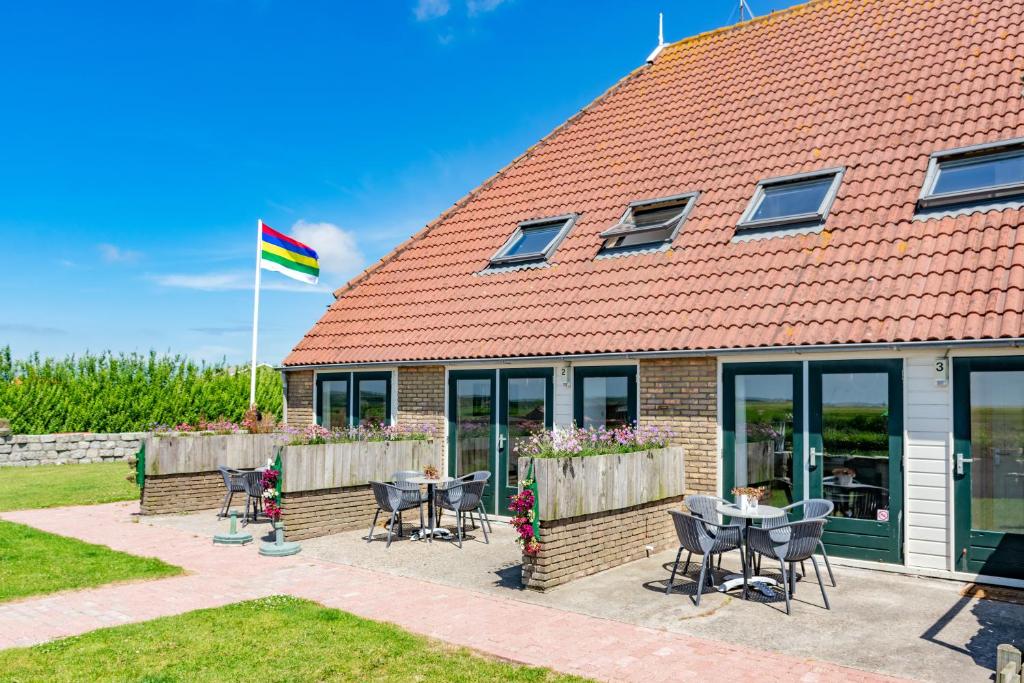 a house with a table and chairs and a flag at De Waddenparel in Kinnum