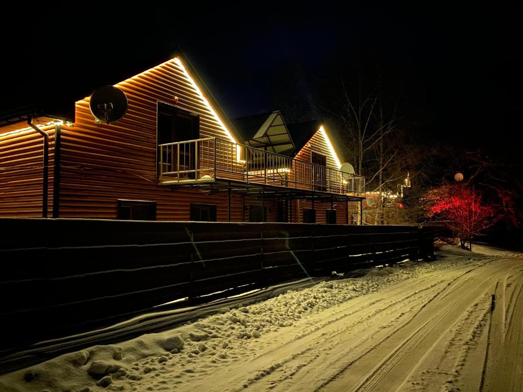 a house with lights on it in the snow at Хочу в Карпати in Skole