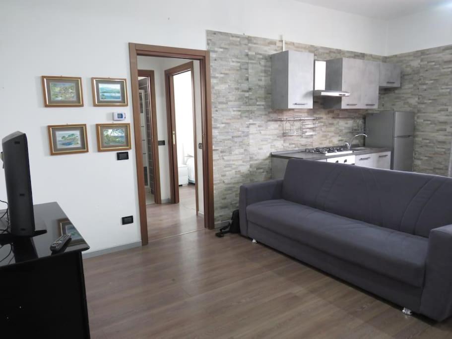 een woonkamer met een bank en een keuken bij La tua casa tra Milano e Como in Caronno Pertusella