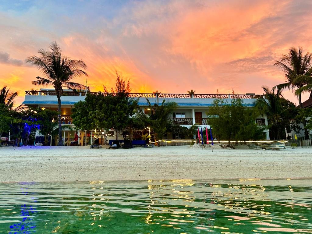 a building on the beach with a sunset at Little Mermaid Dive Resort in Malapascua Island