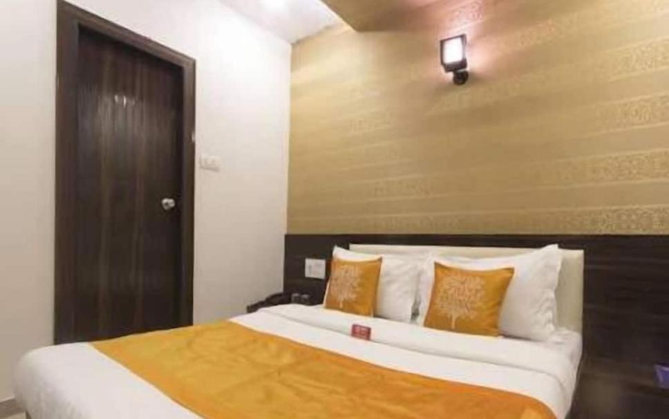 a bedroom with a large bed with orange and white pillows at New Accore Inn Plus By Glitz Hotels in Mumbai