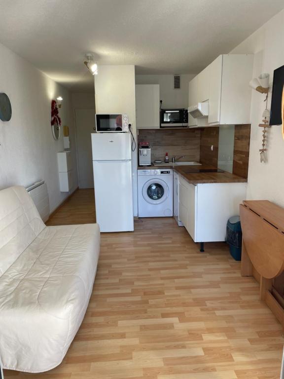 a small kitchen with a white refrigerator and a washer at Studio cabine barcares in Le Barcarès