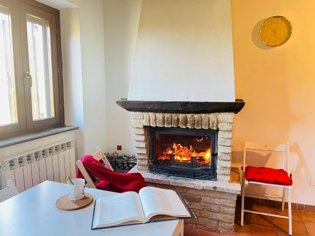 a living room with a fireplace and a table with books at Castelvecchio 172 in Sarnano