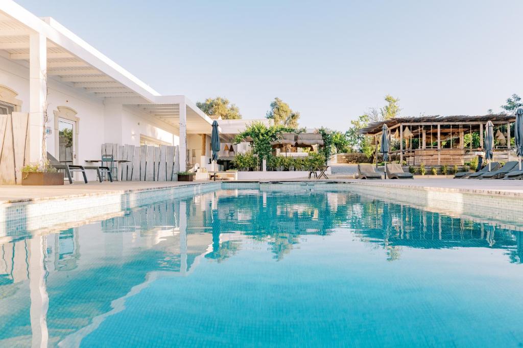 a swimming pool in a house with blue water at Conversas de Alpendre in Vila Nova De Cacela