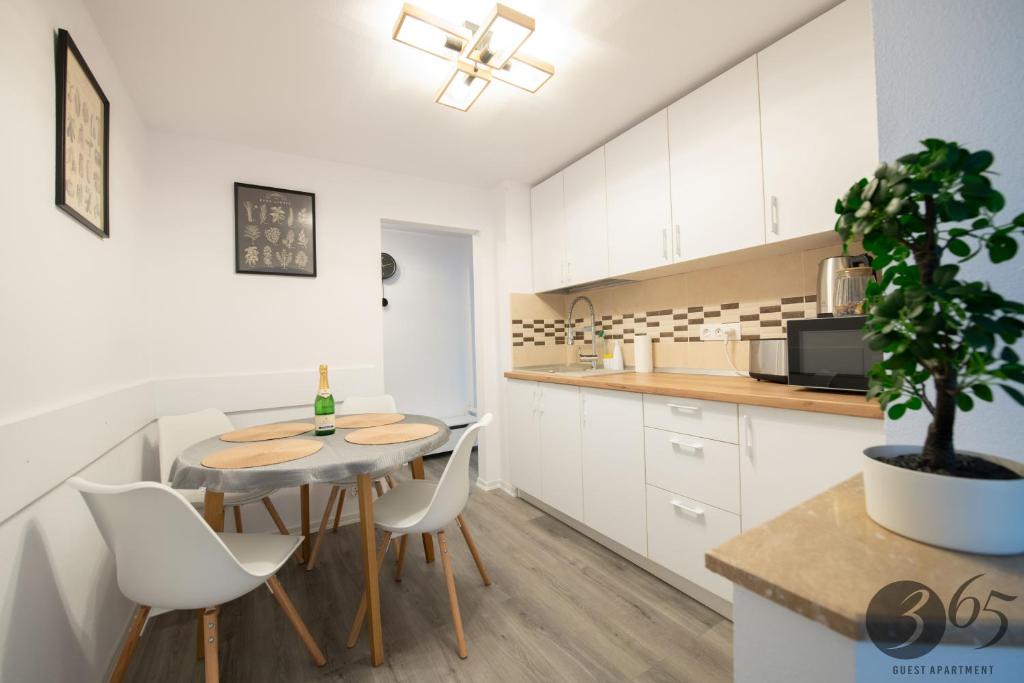 cocina con mesa, armarios blancos y maceta en 365 Guest Apartment, en Hunedoara