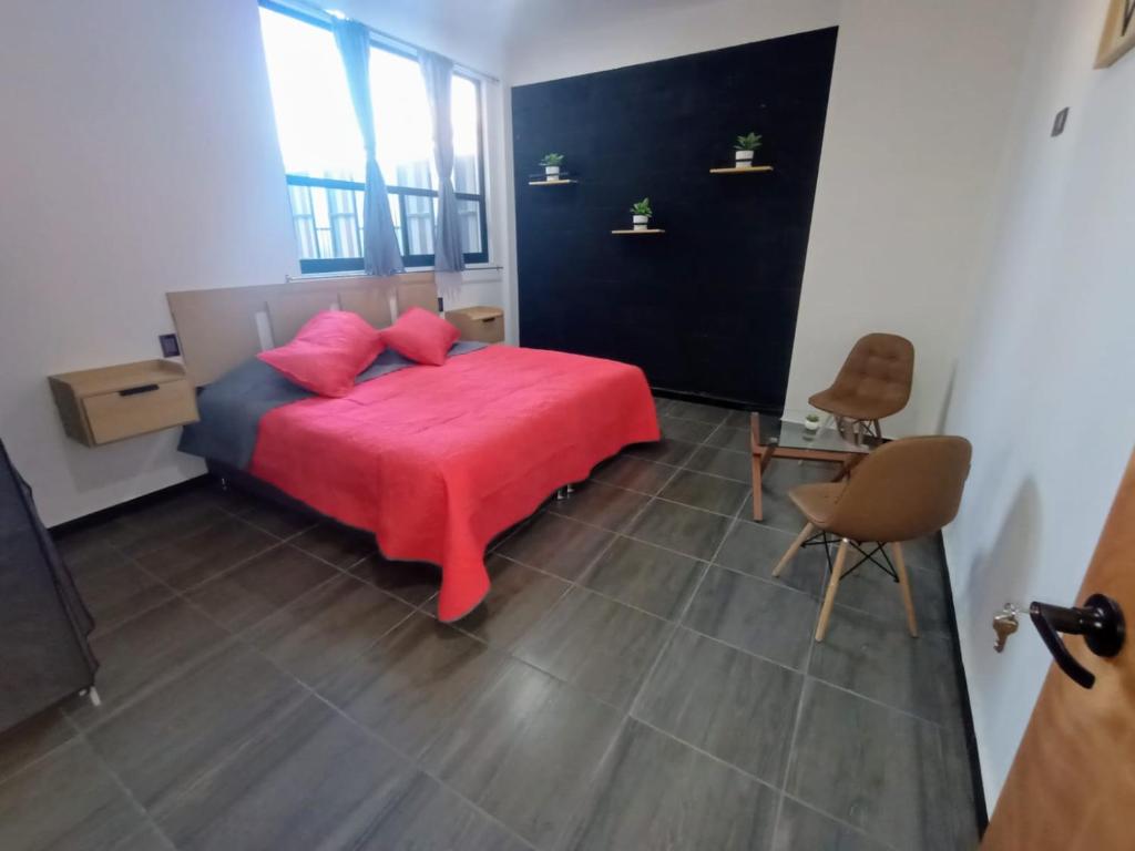 a bedroom with a bed with a red blanket at Suite Departamento Nuevo in Aguascalientes
