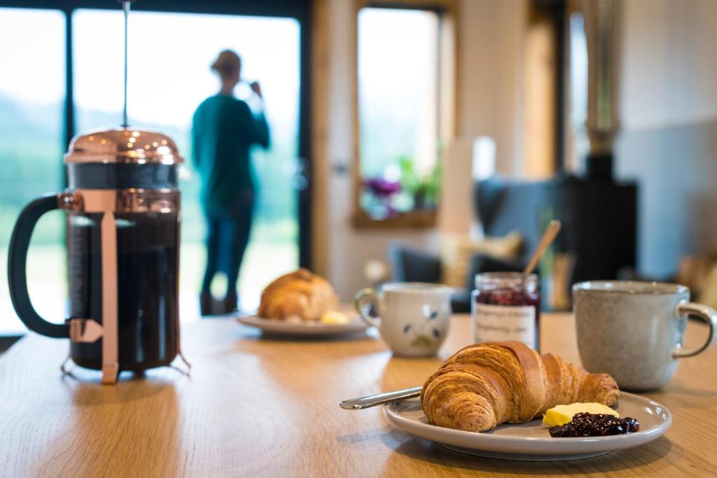 una mesa con un plato de cruasanes y una taza de café en Luxury Cabins at Glenorchy Farm, en Dalmally