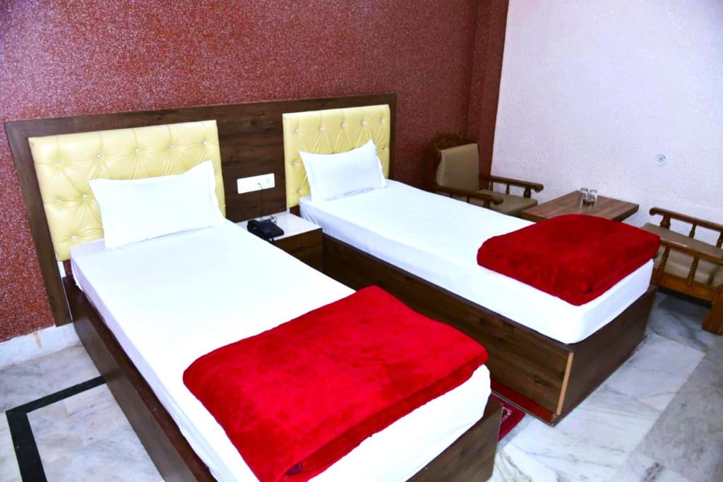 two beds with red sheets in a room at GRG Royal Surya Inn Gaya in Gaya