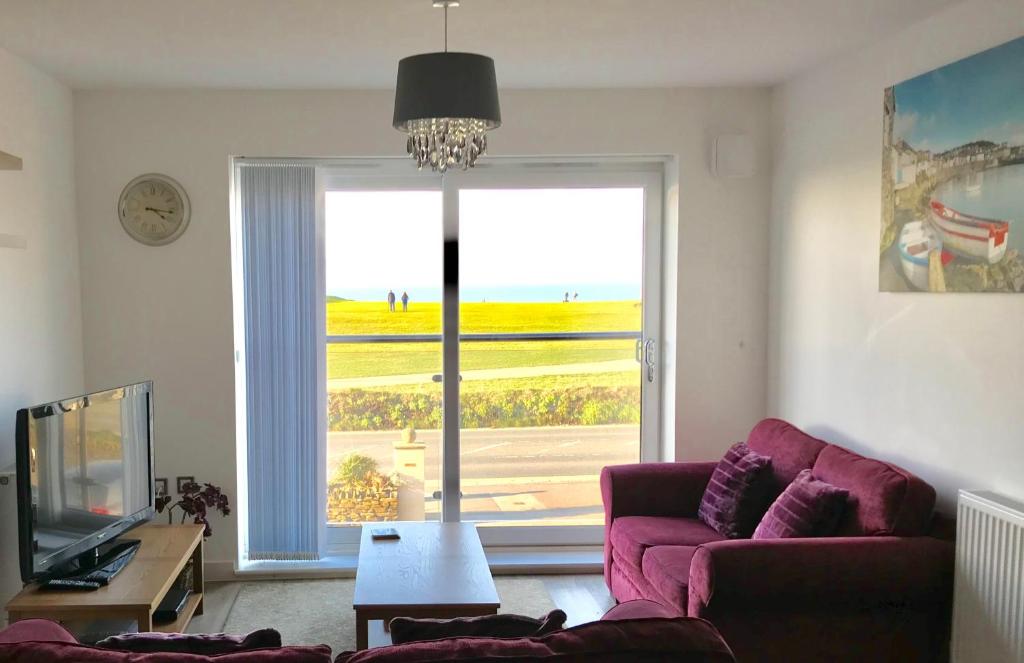 sala de estar con sofá y ventana grande en Alishan Cornwall Holidays en Newquay