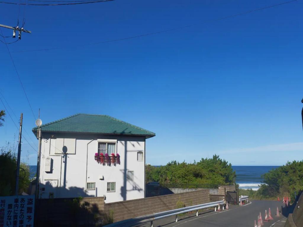 Qiao No,105 - Vacation STAY 75661v في Hokota: مبنى أبيض بسقف أخضر بجوار المحيط