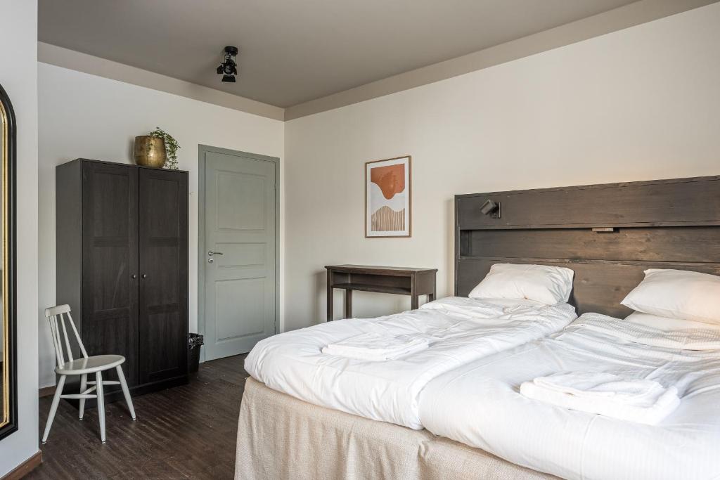 a bedroom with a large white bed with a wooden headboard at Hotell Grelsby Strand in Godby