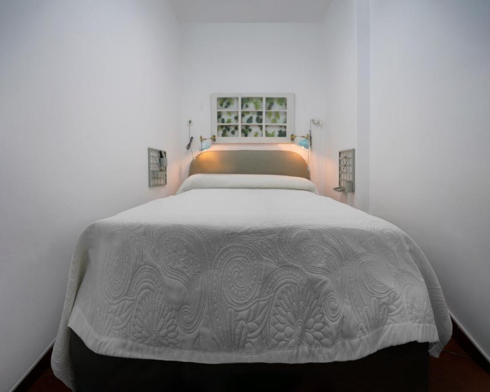 a bedroom with a bed with a white blanket at Playa Chica Beachfront Apartment in Santa Cruz de Tenerife