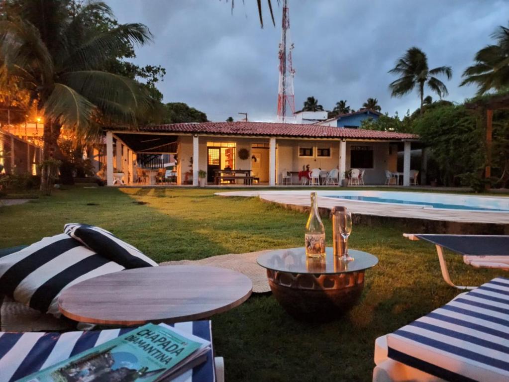 een huis met een zwembad en een tafel met een fles wijn bij Vila Gameleira Garça in Maceió