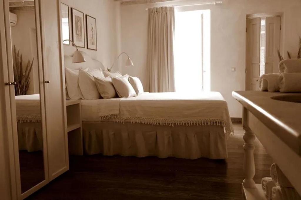 - une chambre blanche avec un lit et une fenêtre dans l'établissement La Maison Kalogera, à Mykonos