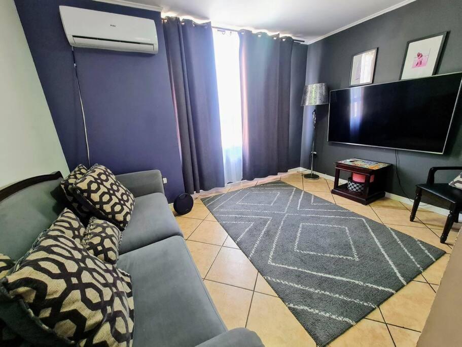 a living room with a couch and a flat screen tv at Casa en condominio jardines del norte Antofagasta. in Antofagasta